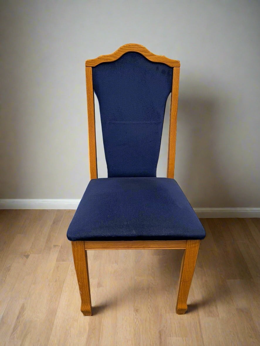 Chair with blue cushioned seat and backrest on a wooden floor against a plain wall.