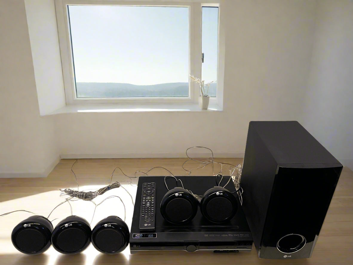 Black home theater system with speakers against a gray brick wall.
