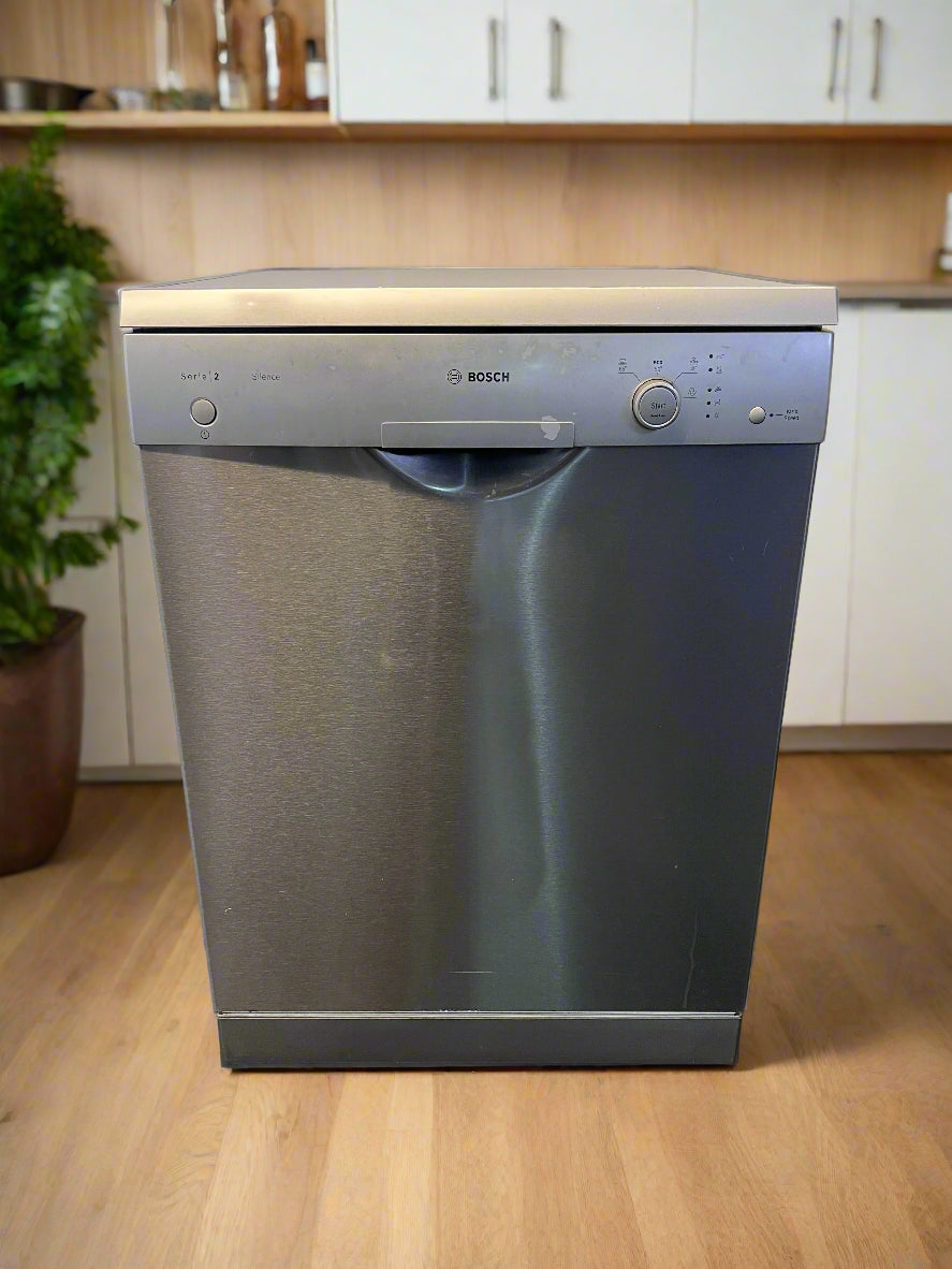 Bosch dishwasher in a kitchen setting with wooden cabinets and a plant.