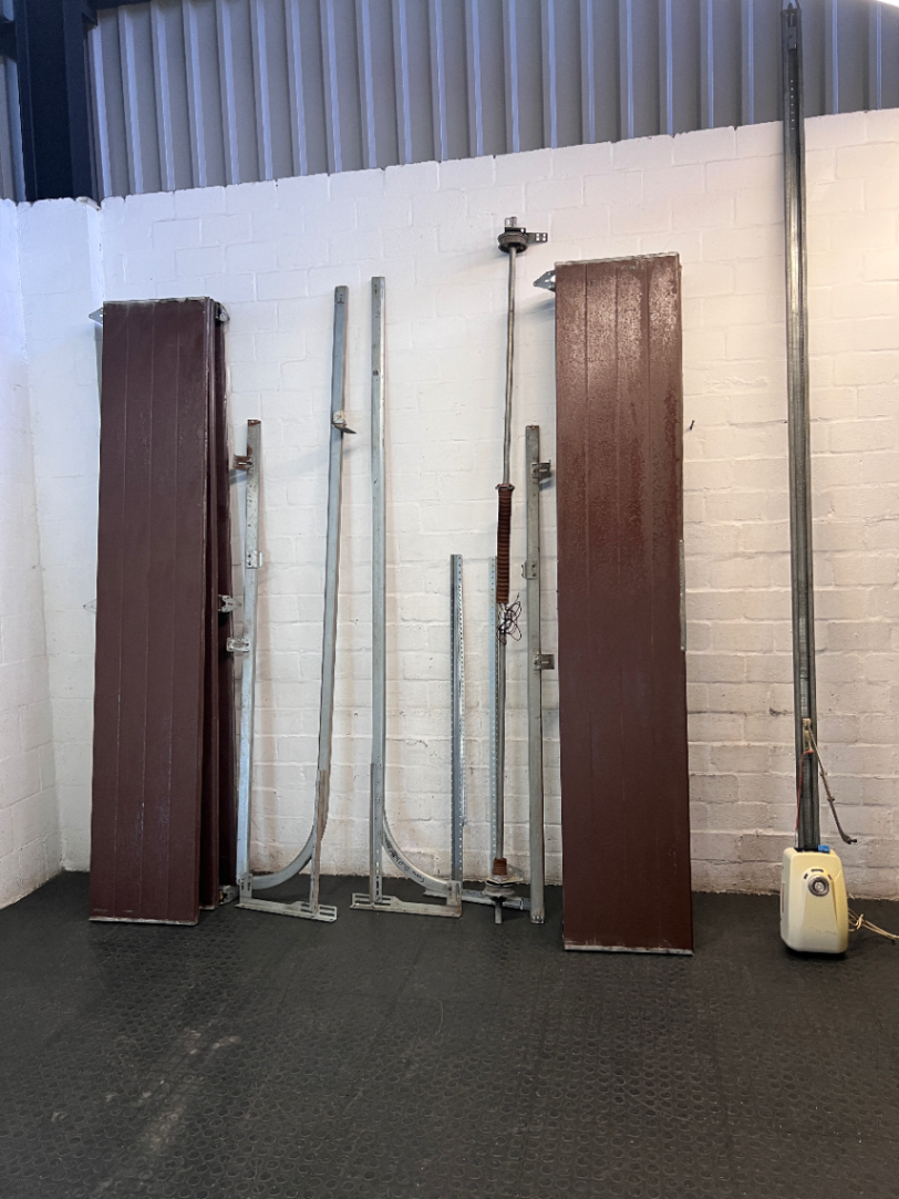 Brown Metal Sectional Garage Door with Motor and Tracks — One Door With Snapped Tensioner; Both Motors Working