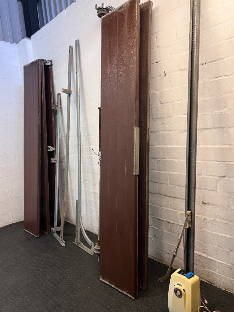 Brown Metal Sectional Garage Door with Motor and Tracks — One Door With Snapped Tensioner; Both Motors Working