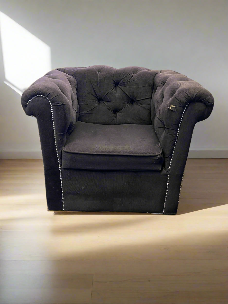 Gray armchair with tufted backrest on a wooden floor