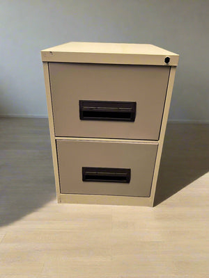 Beige two-drawer filing cabinet against a gray brick wall.