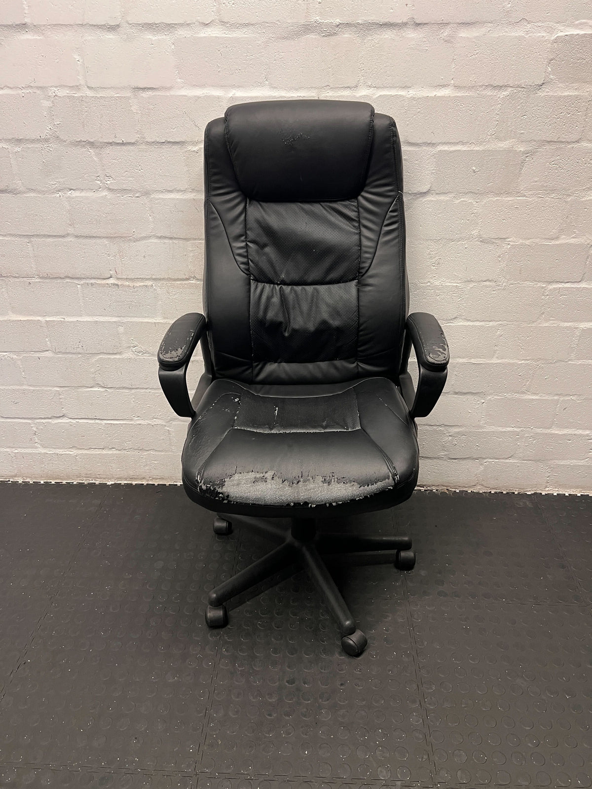 Black office chair against a gray brick wall.