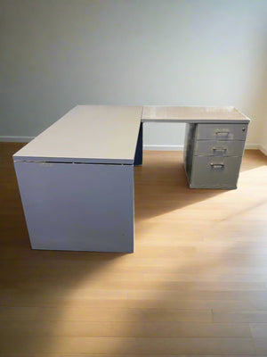 Gray L-shaped desk with a white brick wall background