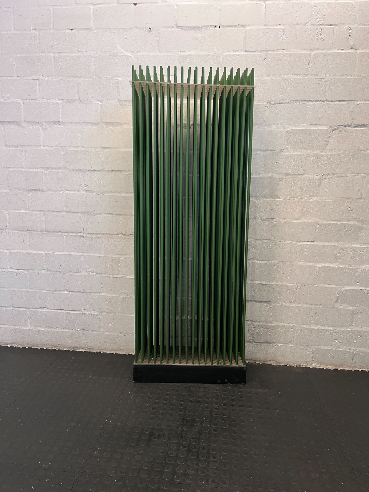 Green metal radiator against a white brick wall
