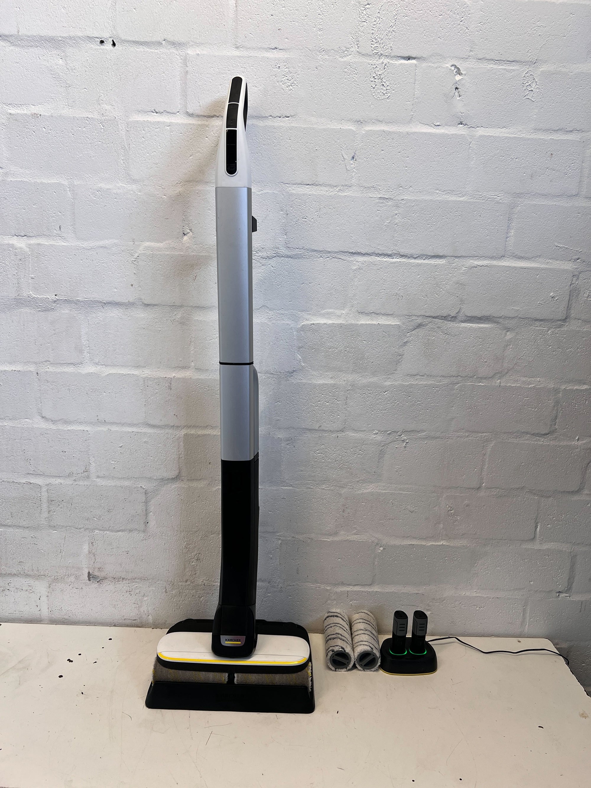 Cleaning device with attachments on a white surface against a white brick wall