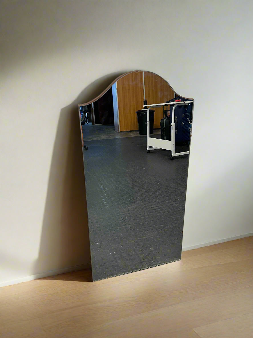 Wall-mounted mirror with a wooden frame on a plain wall.