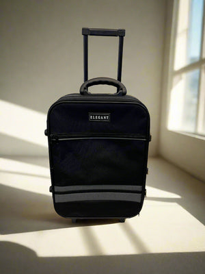 Black suitcase with 'Elegant' branding on a light floor with sunlight casting shadows.