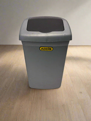 Gray trash bin with a black lid on a light gray floor and background