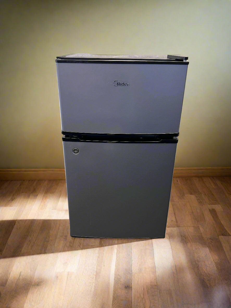 Small refrigerator on a wooden floor against a yellow wall