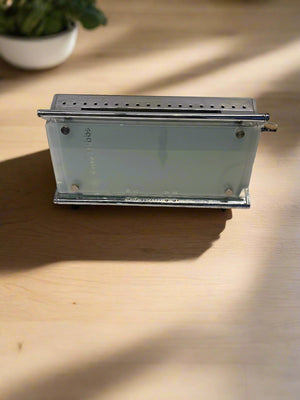 Small metal box with glass front on a wooden surface