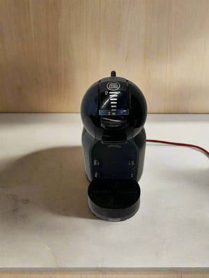 Black coffee machine on a white countertop with a wooden wall background