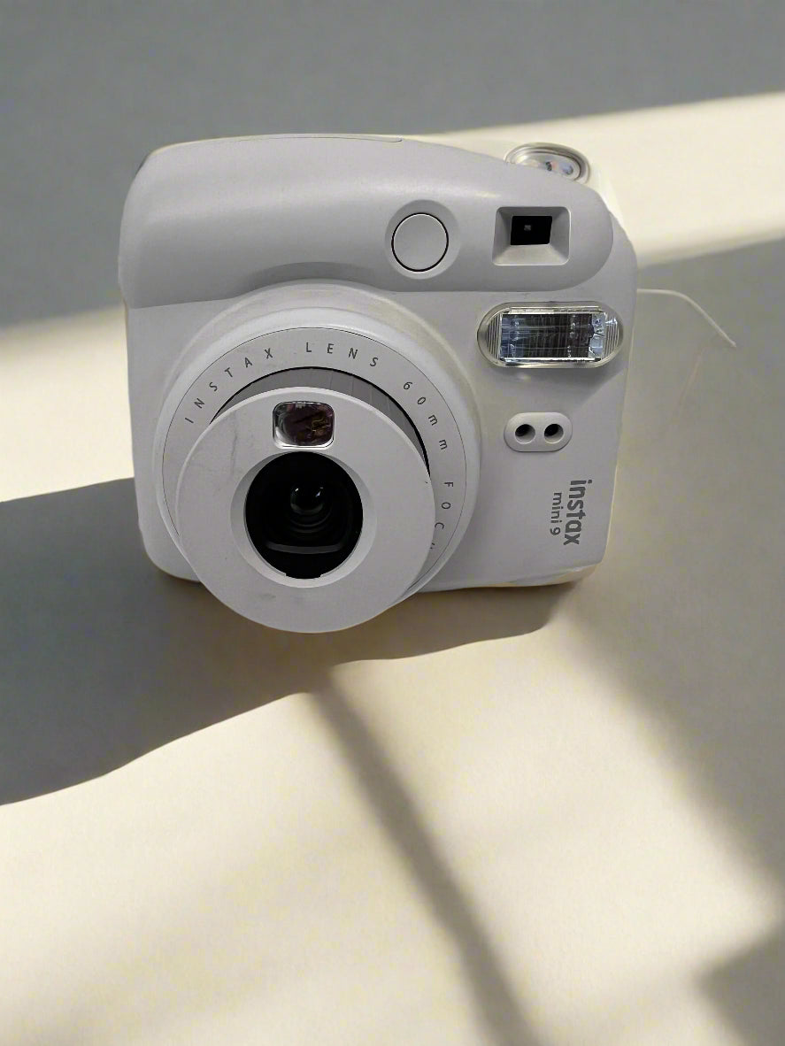 White instant camera on a light surface with a soft shadow