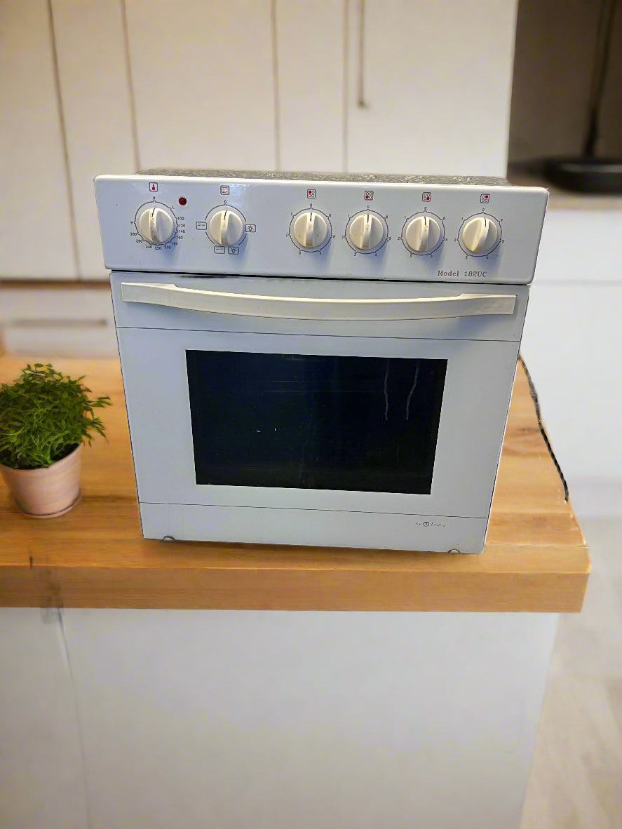 White oven on a wooden countertop with a plant in the background