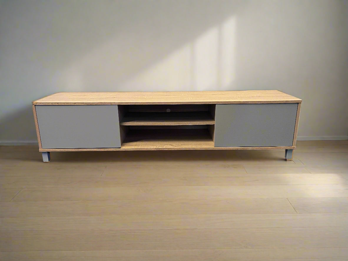Wooden TV stand with gray doors on a wooden floor.