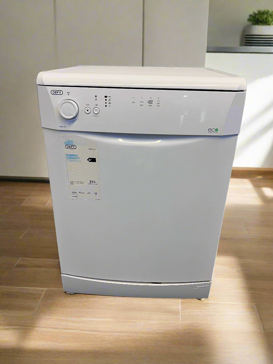 White dishwasher with control panel and labels on a gray floor against a white brick wall.