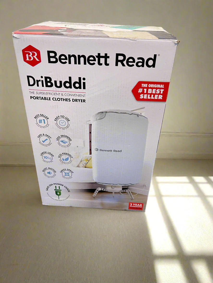 Bennett Read DriBuddi portable clothes dryer packaging on a black surface with a gray concrete wall background.