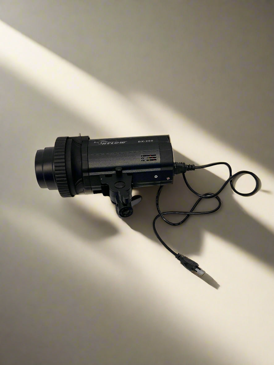 Black camera lens with attached cable on a light gray background