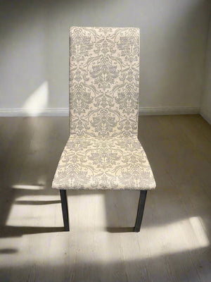 Chair with patterned backrest against a brick wall.