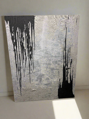 Abstract art piece with black and white paint on a textured gray background