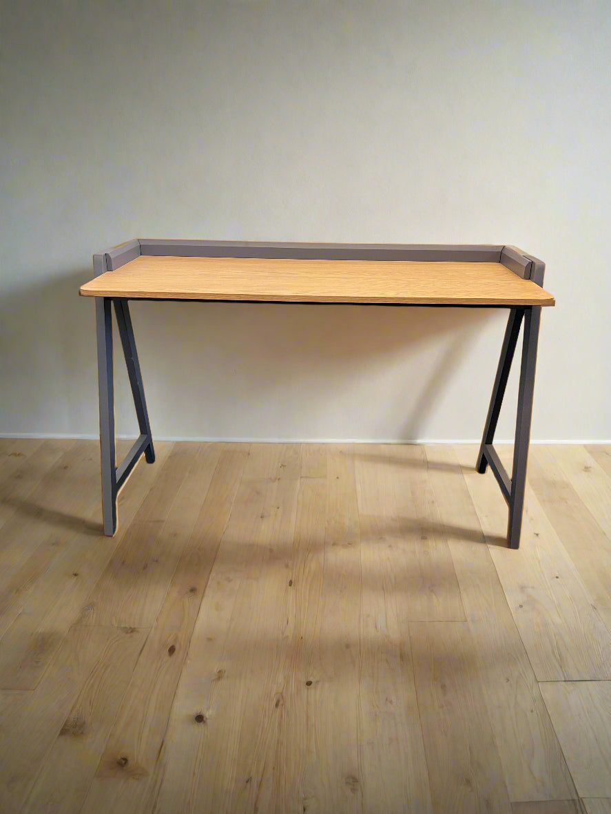 Wooden desk with metal legs on a wooden floor against a plain wall