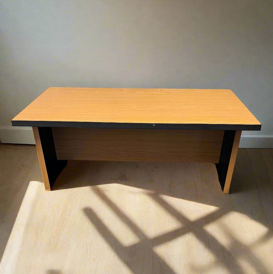 Wooden table with black base against a plain wall