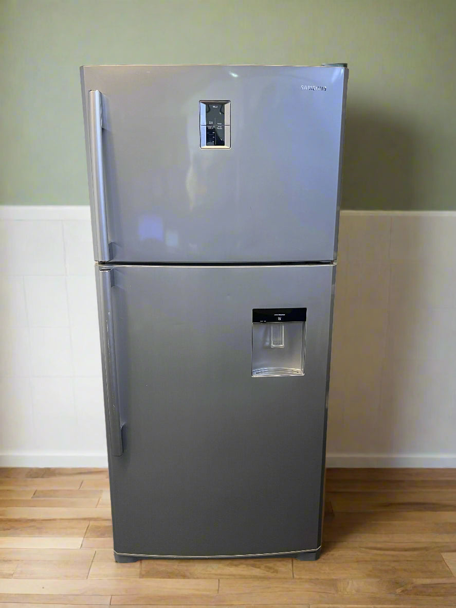 Silver refrigerator with water and ice dispenser on a wooden floor against a green wall.