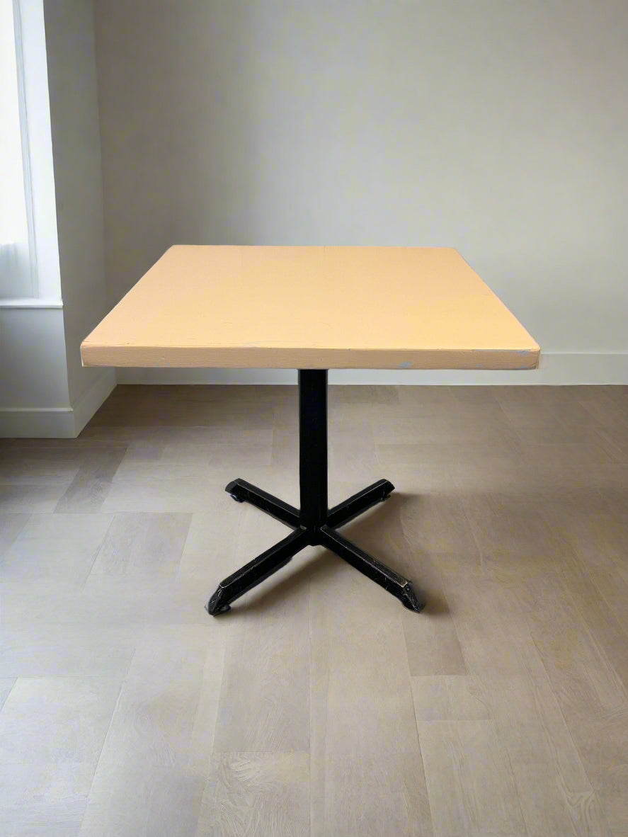 Light wooden table with black metal base on a neutral background