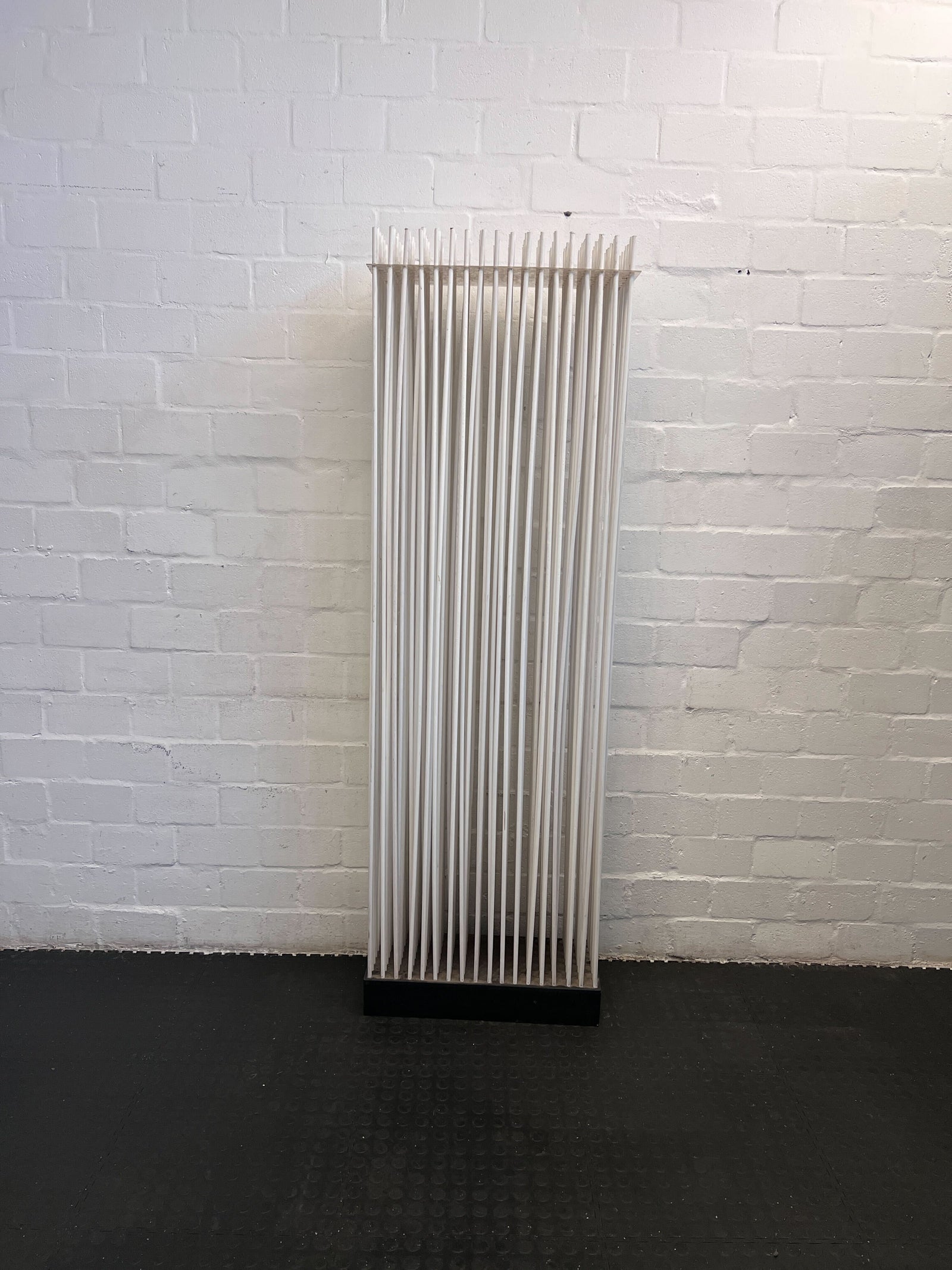Vertical radiator against a white brick wall