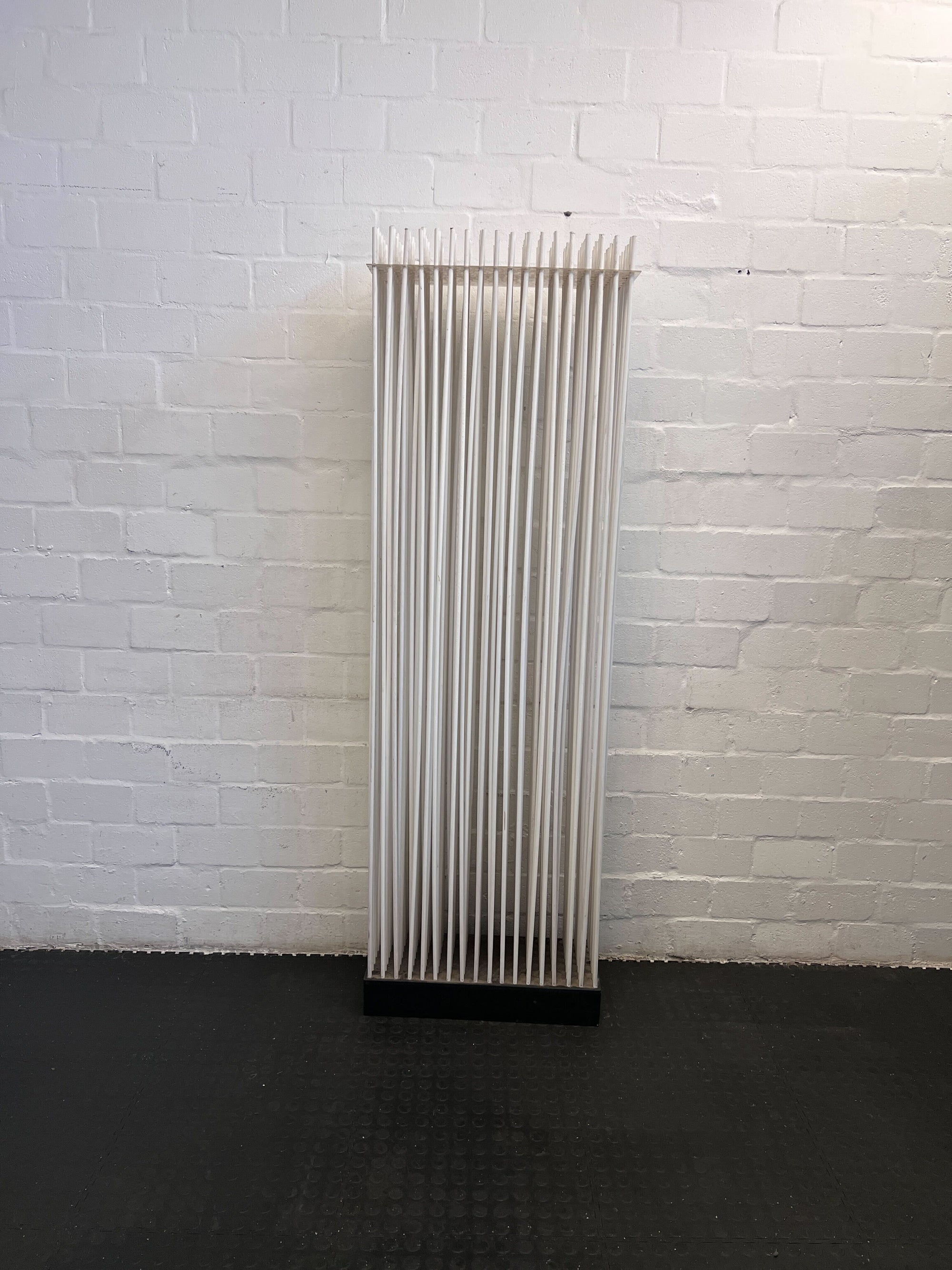 Vertical radiator against a white brick wall