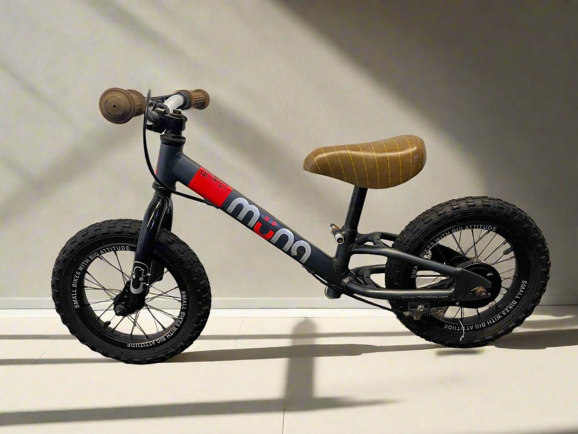 Children's balance bike with wooden handlebar and seat on a light background