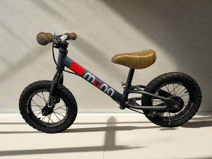 Children's balance bike with wooden handlebar and seat on a light background