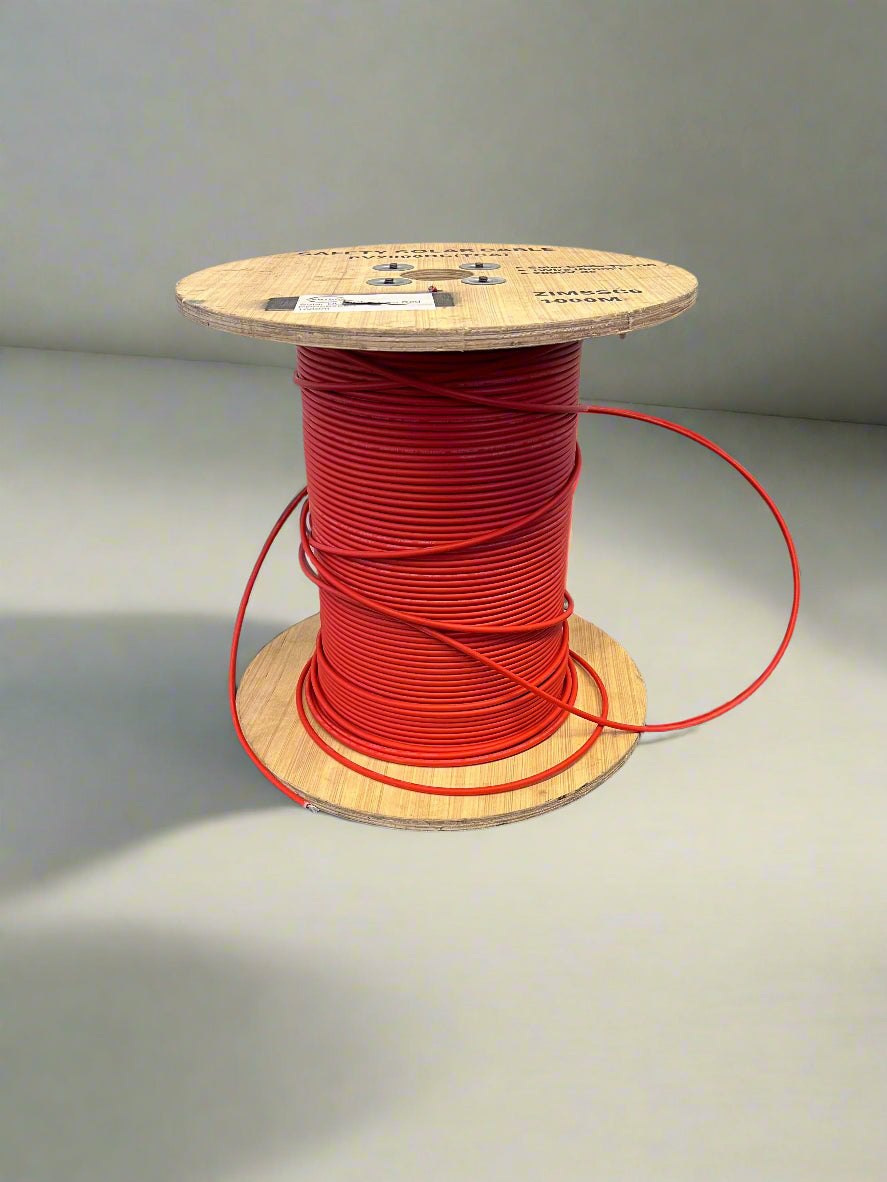 Spool of red wire on a wooden reel against a gray background
