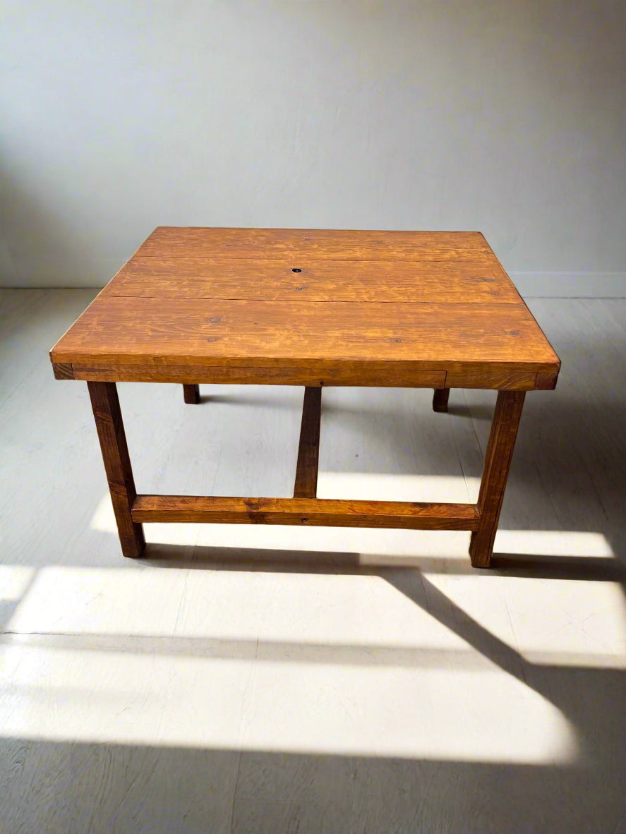 Wooden table with a dark finish on a gray floor against a light gray brick wall.