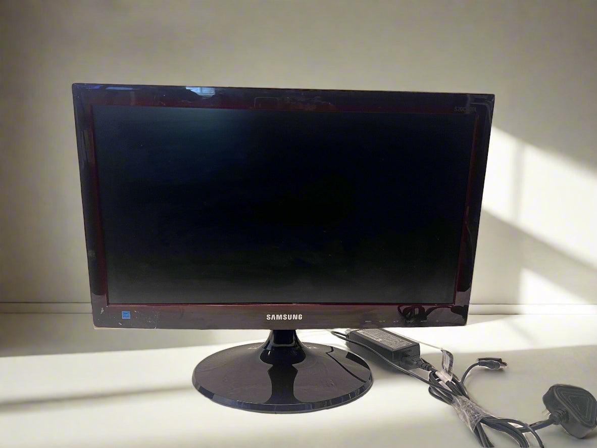 Samsung monitor on a desk with a white wall background