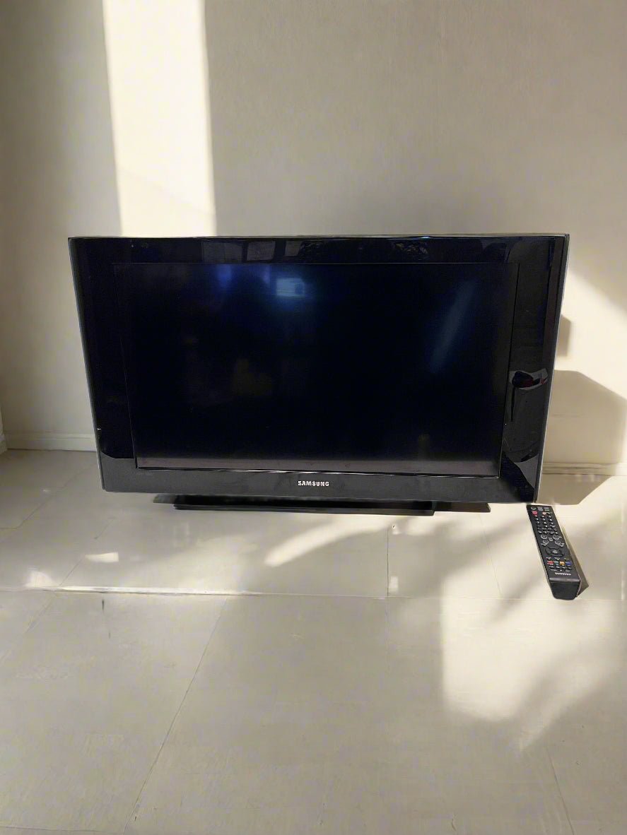 Black Samsung TV on a white table with a brick wall background