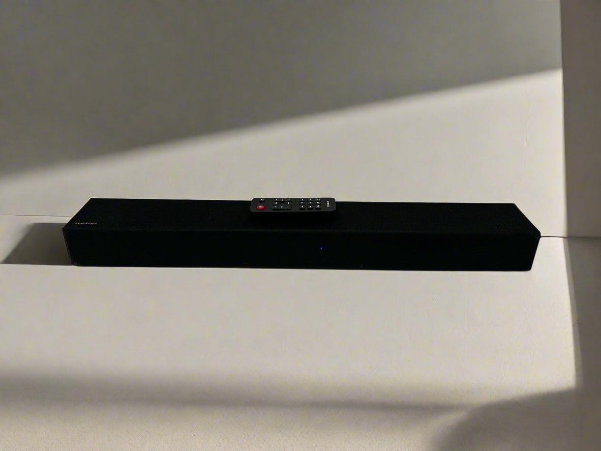 Black soundbar with remote control on a light surface