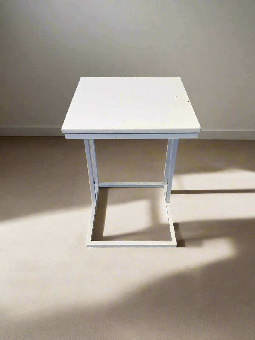 White table on a plain floor with a light gray wall