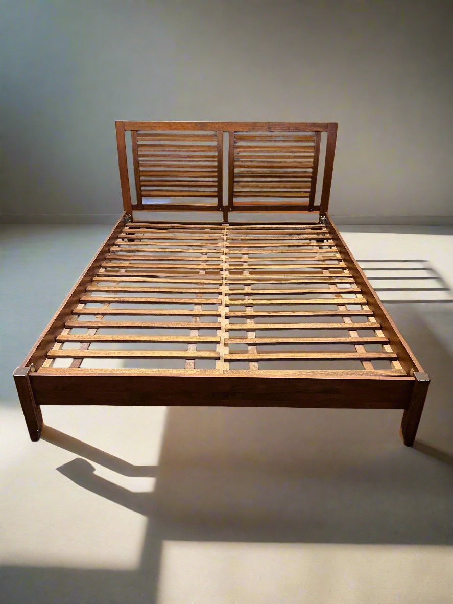 Wooden bed frame on a plain floor with a light background