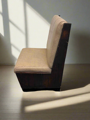 Beige cushioned chair against a white brick wall.