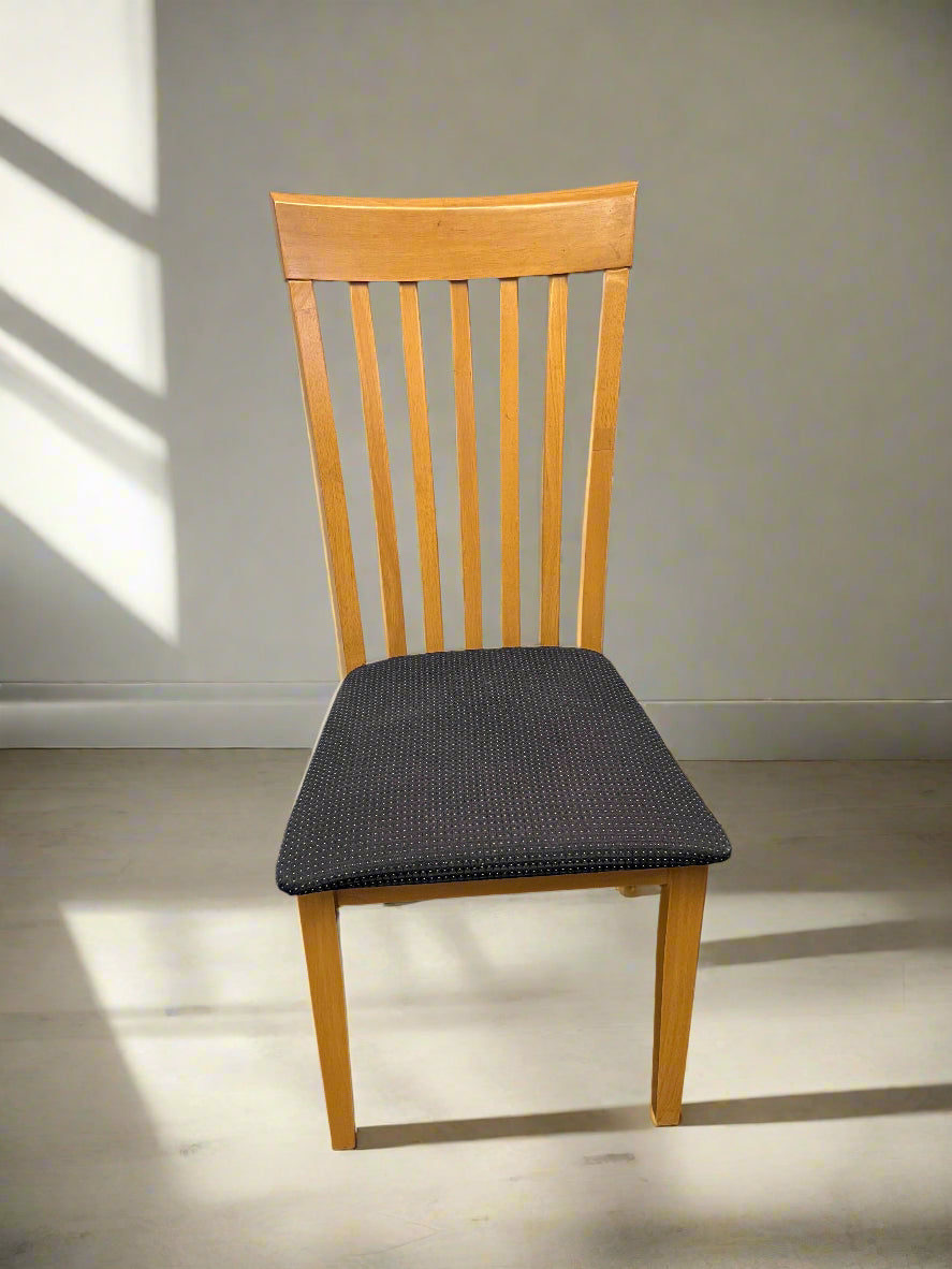 Wooden chair with a black cushion on a plain floor and wall background