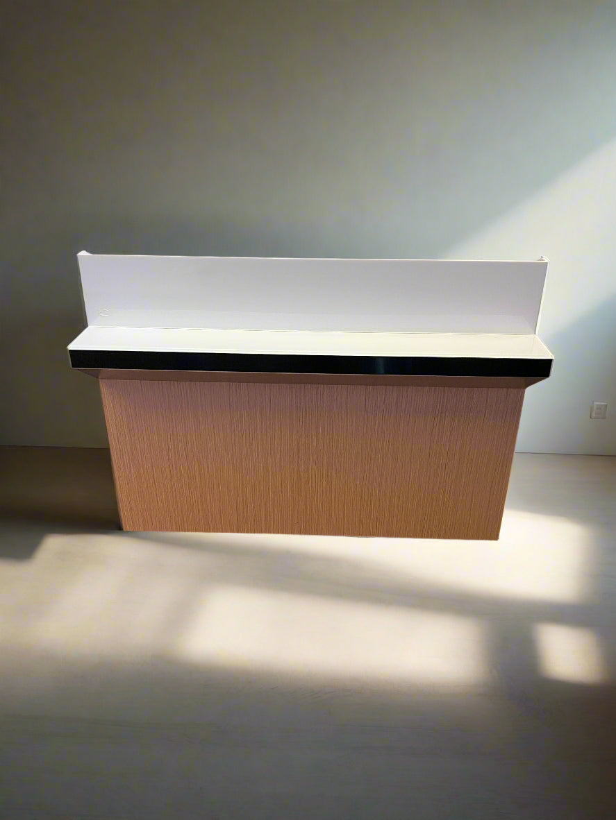 Reception desk with a white backrest against a white brick wall.
