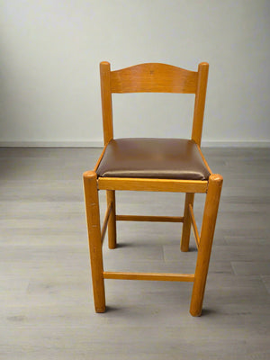Wooden chair with a brown cushion on a plain floor.