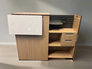 Wooden office desk with a white cabinet against a brick wall.