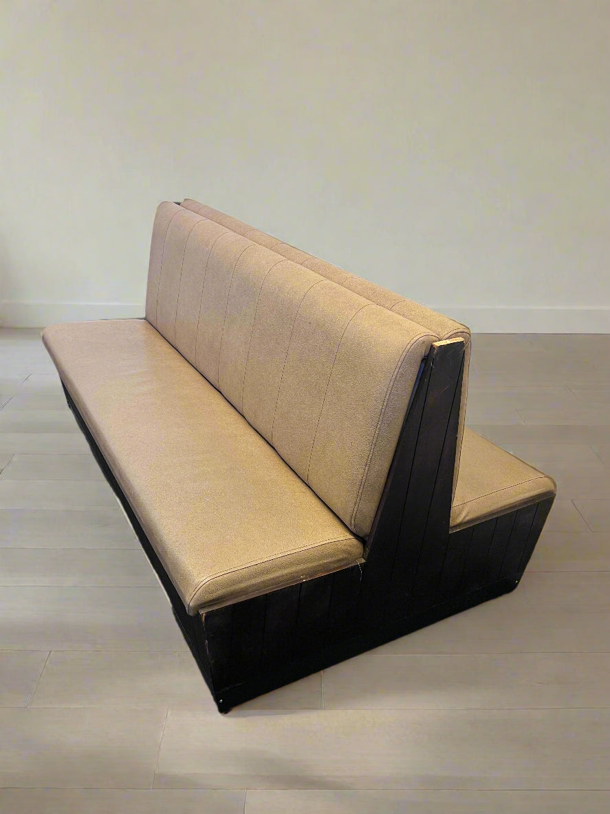 Beige and black bench against a white brick wall.