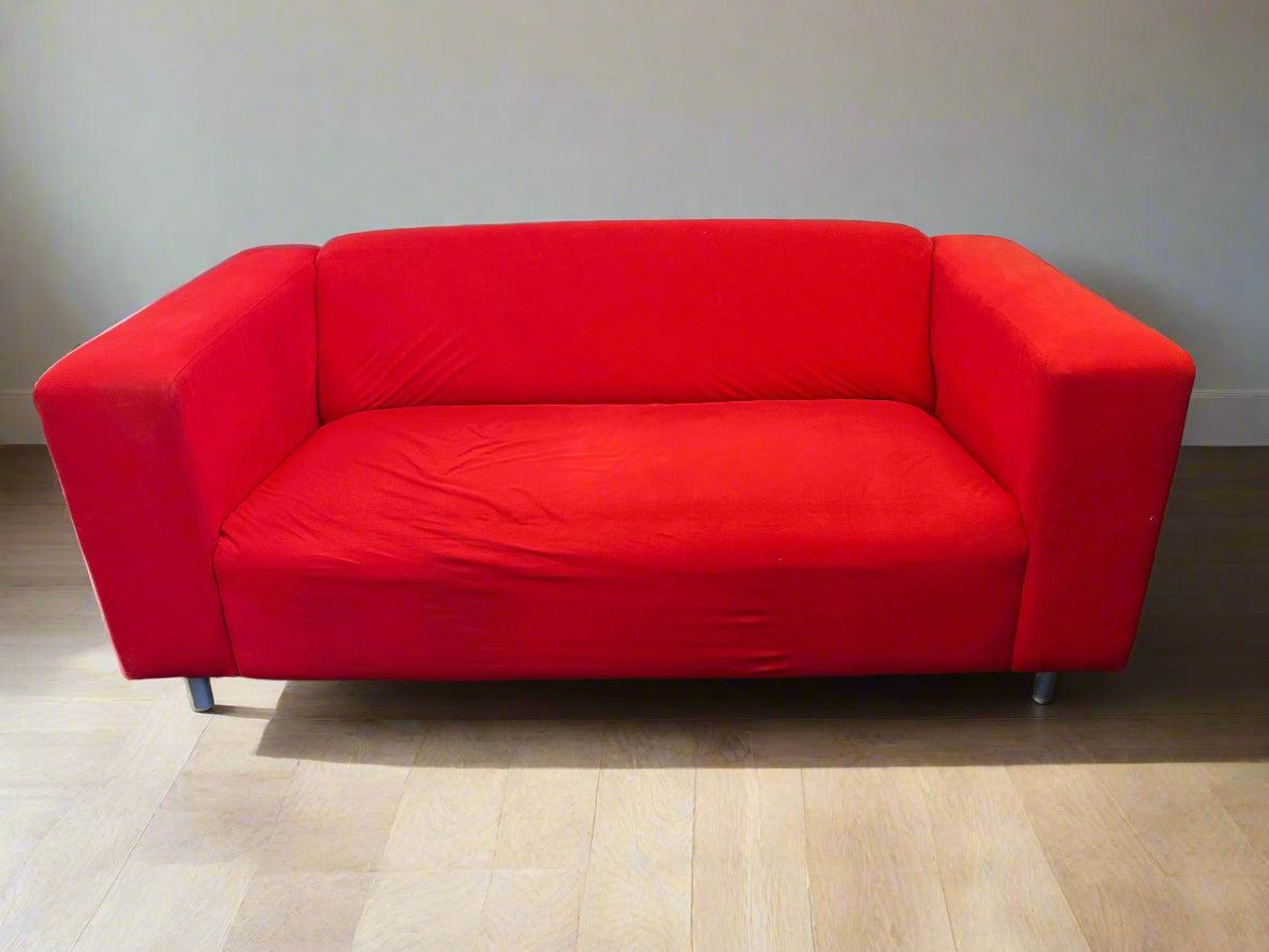 Red sofa on a wooden floor with a plain wall background
