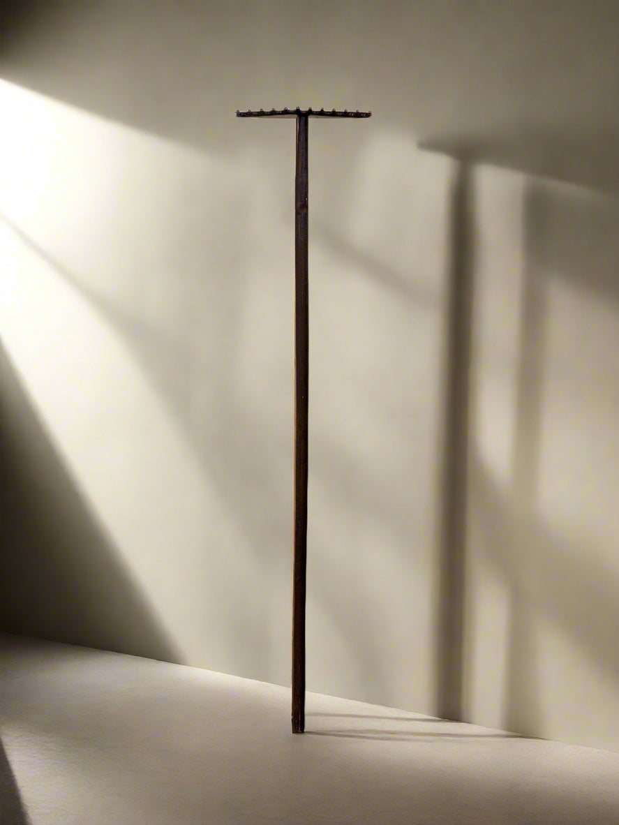 Tall, thin metal stand against a light wall with soft shadows