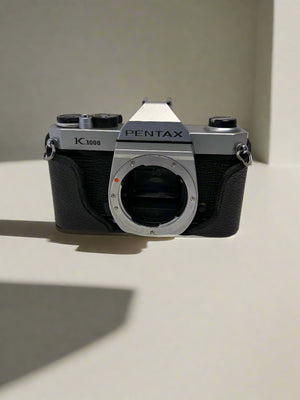 Pentax camera on a concrete floor with a textured wall background