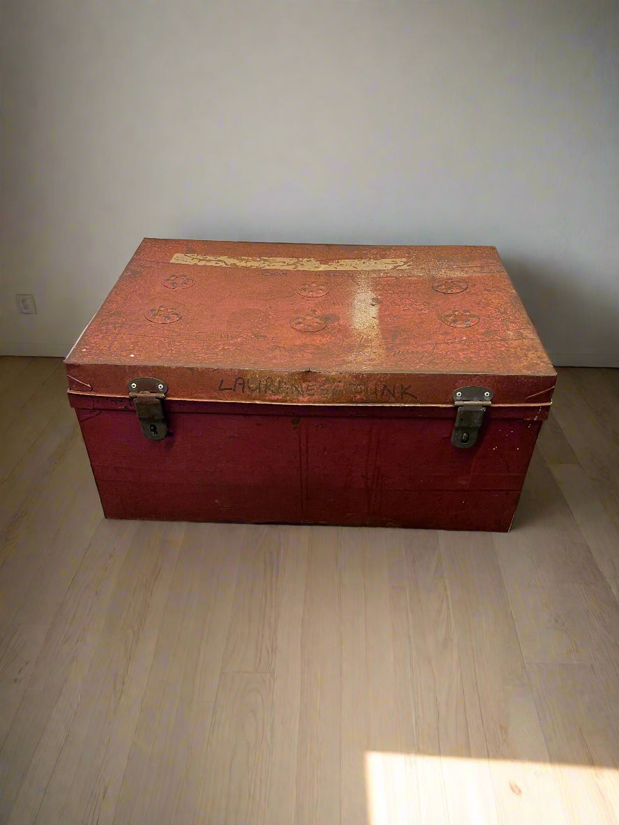 Vintage red trunk on a wooden floor with a plain wall background